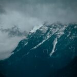 Mountain Landscapes - A dramatic view of snowy mountain peaks shrouded #1726953
