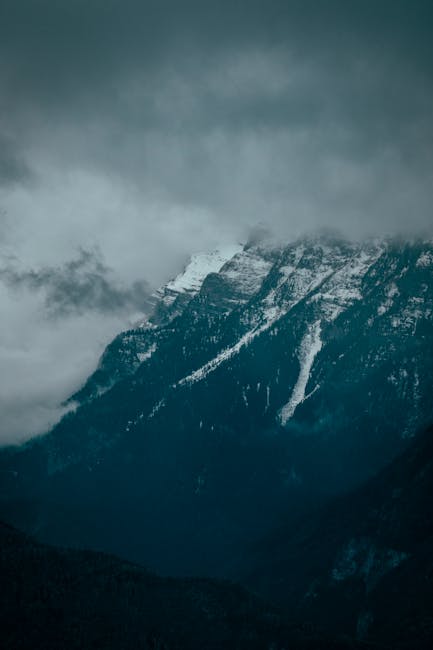 Mountain Landscapes - A dramatic view of snowy mountain peaks shrouded #1726953