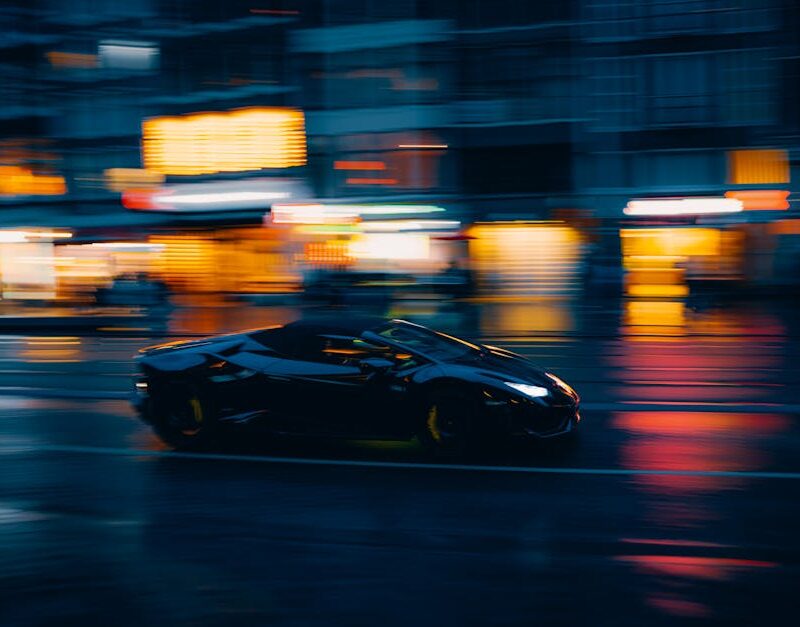 Luxury Cars - A sleek black sports car zooms through a vibrant #35319488