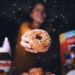 Food Aesthetics - A person holding a donut with vibrant sprinkles  #4707237